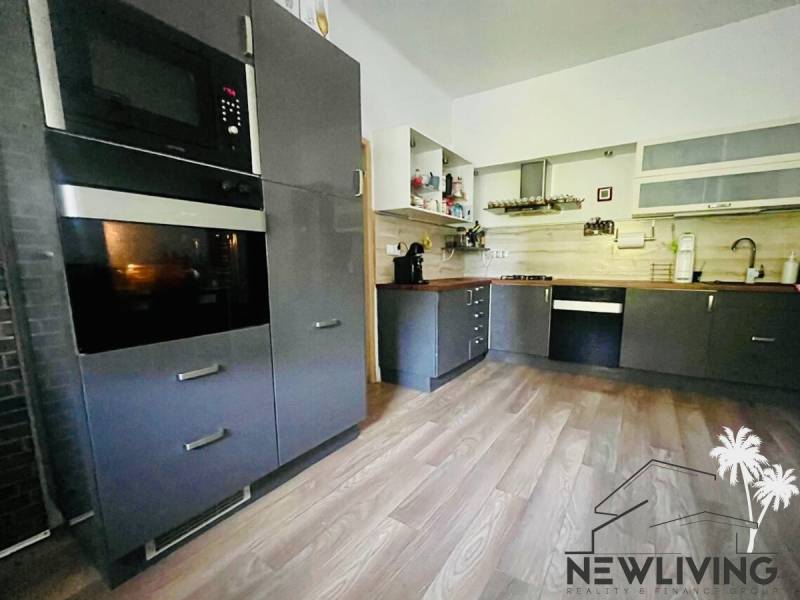 A kitchen in a 3-room apartment with a wooden decor floor and modern equipment.