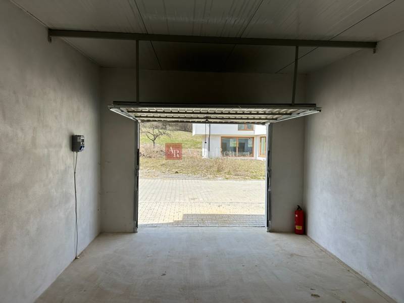 The interior of the garage has a white wall, concrete floor, and open doors.