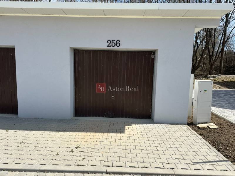 Garages in Liptovské Kľačany, simple design, white facade, brown gate, and paving.