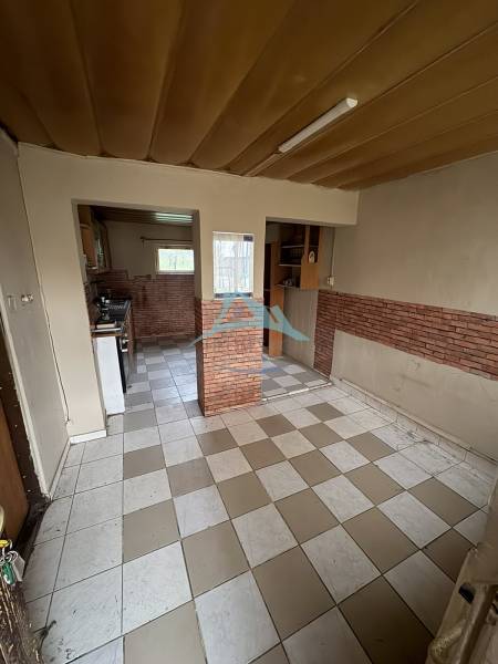 A kitchen and dining area in a family house with a tiled floor and brick cladding.