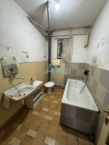 A bathroom in a family house with a bathtub and a sink, simple design with tiles.