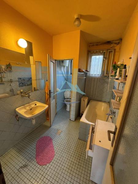 A bathroom in a family house with a bathtub, sink, and toilet in light tones.