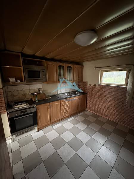 A kitchen in a family house with a kitchen unit, tiles, and appliances.