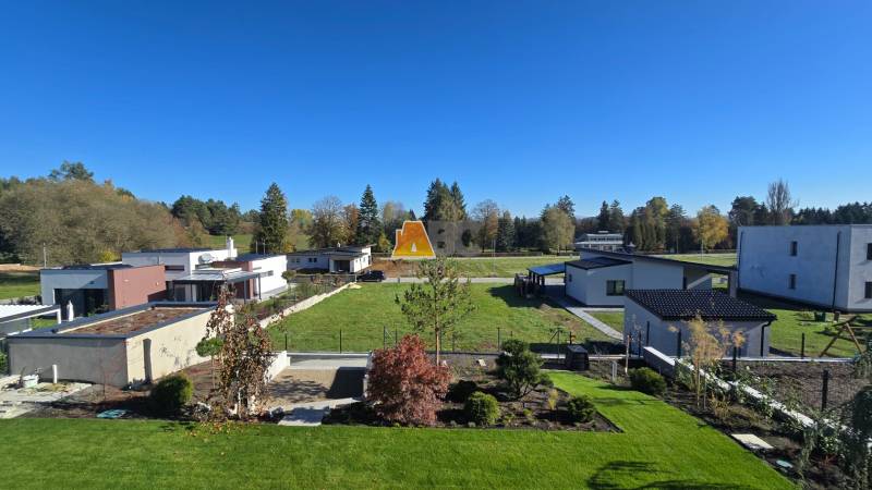Residential plots in Kováčová with modern houses, landscaped gardens, and greenery.