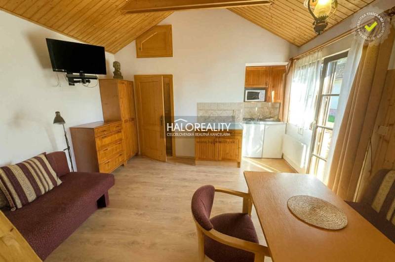 The interior of a cabin with a wooden decor floor, a dining table, and a television.