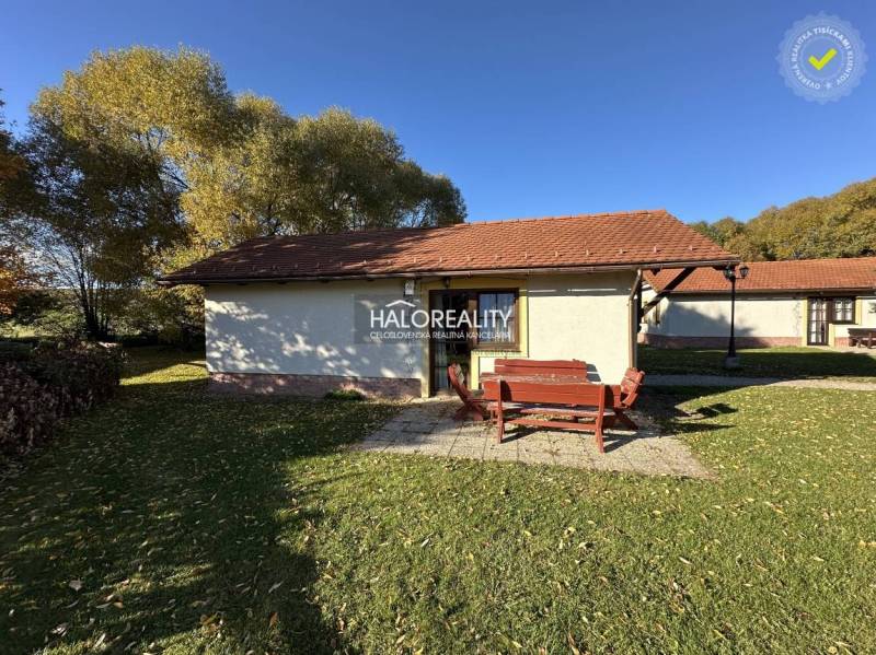 A cottage in Liptovský Mikuláš surrounded by an autumn garden and a pond with a wooden bridge.