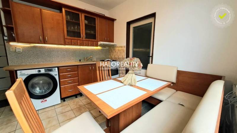 A kitchen in a studio apartment with a wooden decor and a corner sofa.