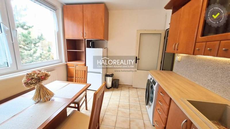 A kitchen in a studio apartment with ceramic tiles and a wooden decor kitchen unit.