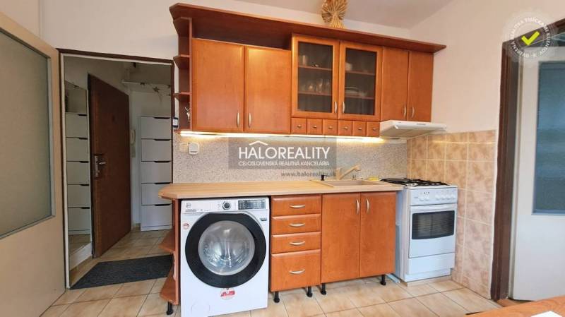 Kitchen unit with wood decor, washing machine and stove in a studio apartment.
