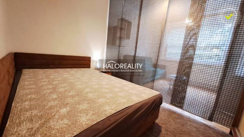 Furnishing a bedroom in a studio apartment with carpeted flooring and dark curtains.