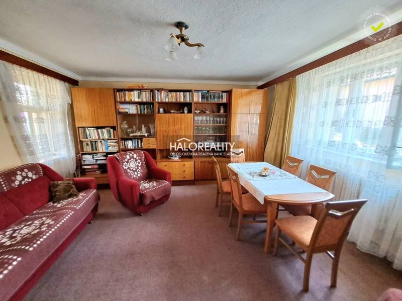 Living room with carpeted floor, red sofa, and bookshelf in a family house.