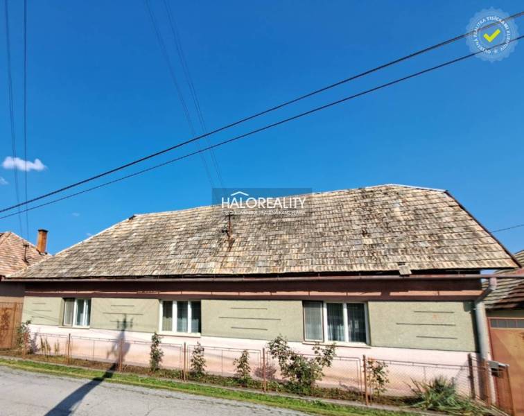 A family house in Zvolen with a gable roof and a wooden fence in front of the house.
