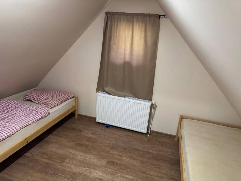 The attic of the cottage with two beds and a curtain.