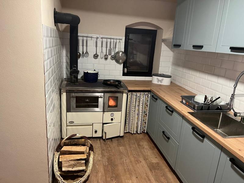 Rustic kitchen in a cabin with wooden decor and a wood-burning stove.