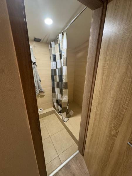 A cottage with a bathroom, shower, and bright tiled floor with a wood decor.