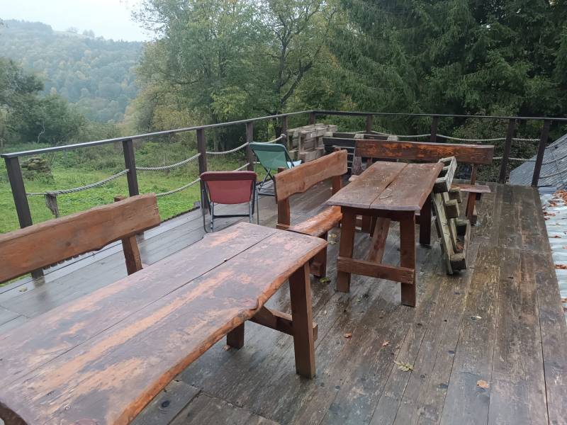 Wooden benches and tables on the terrace with a view of the forest near the cottage in Píla.