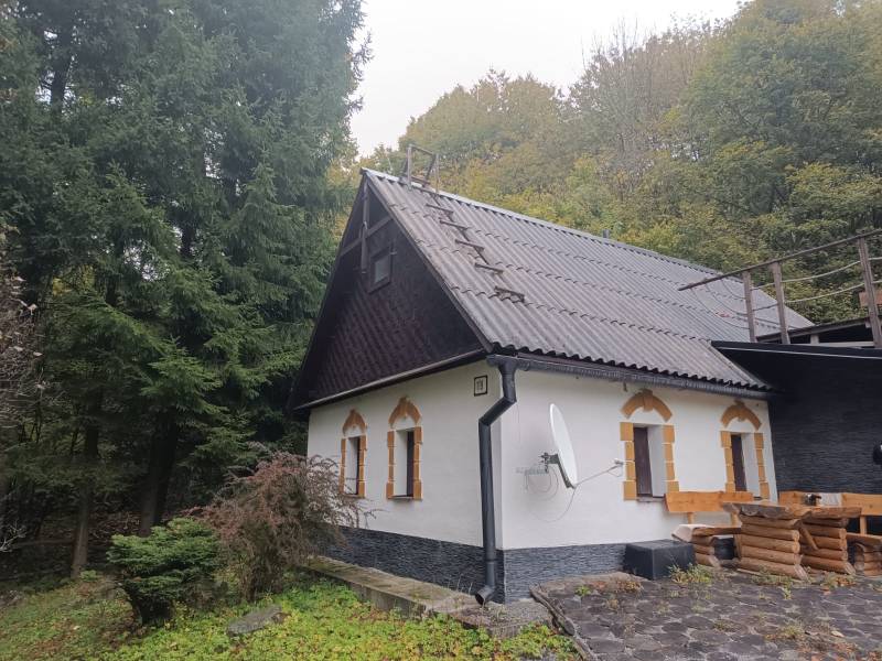 A cottage in the village of Píla surrounded by forest and a stone path.