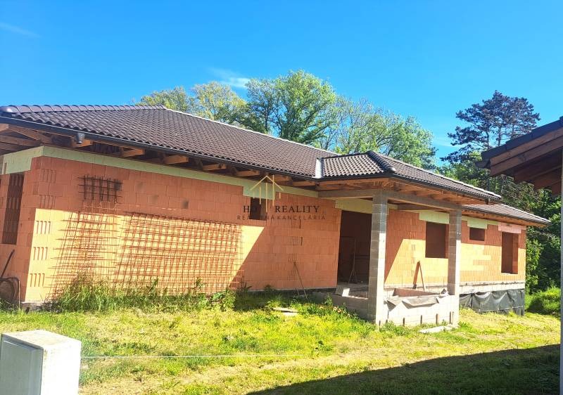 Family house in Hokovce under construction with a roof and brick walls.