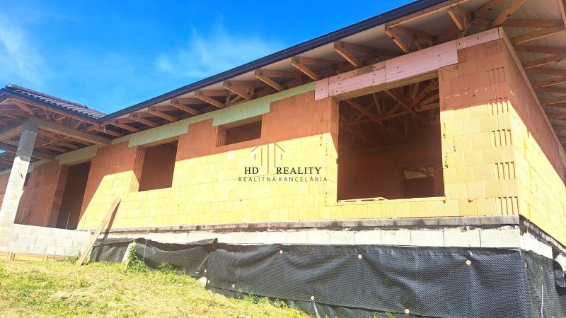 An unfinished family house in Hokovce with a brick structure and a roof with wooden beams.