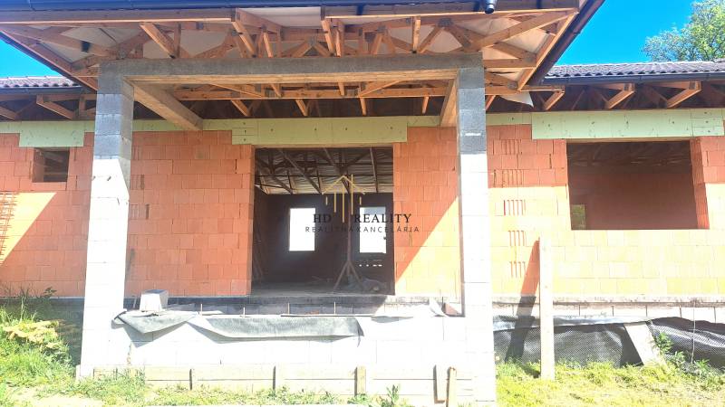 Unfinished family house in Hokovce with unplastered brick walls and exposed roof structure.