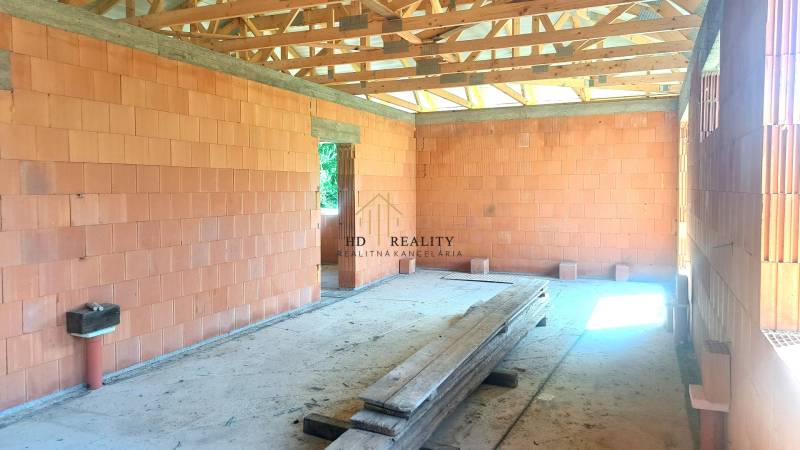 An unfinished construction of a family house with bricks and wooden beams.
