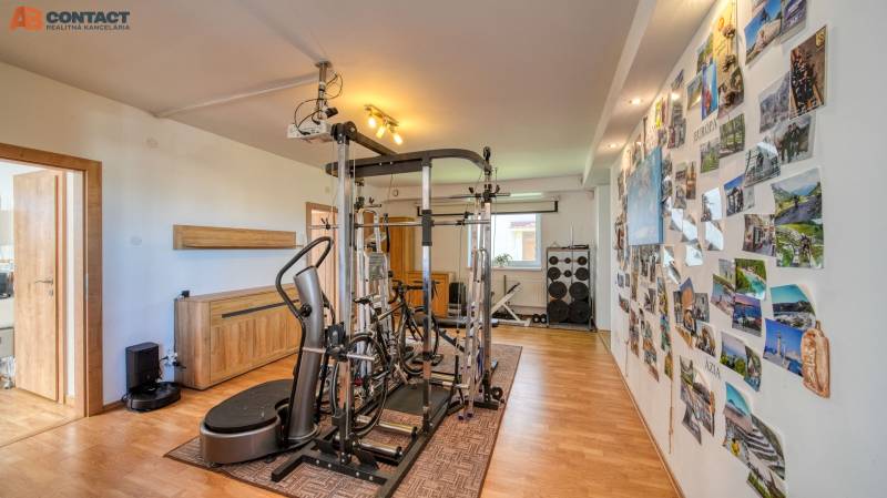 A room in a family house with fitness equipment and a wall full of photographs on a floor with wooden decor.