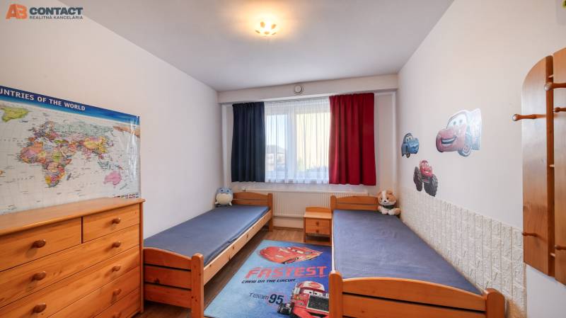 Children's room in a family house with separate beds, wooden furniture, and car decorations.