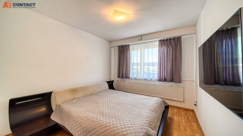 Bedroom in a family house with a bed, a wall-mounted television, and flooring with a wooden decor.