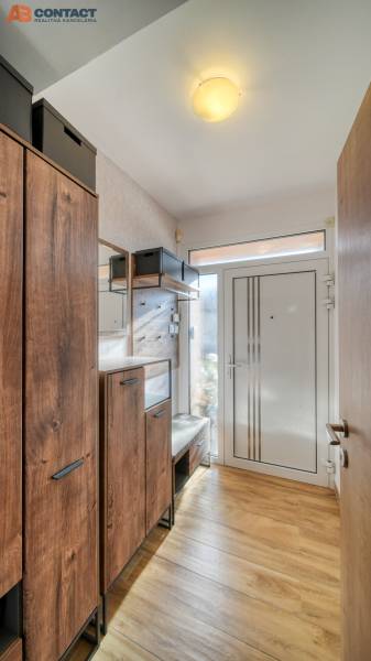 The hallway in the family house contains a wardrobe, a shoe cabinet, and a floor with a wooden decor.