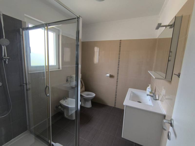 Bathroom in a 3-room apartment with a glass shower, sink, and toilet.
