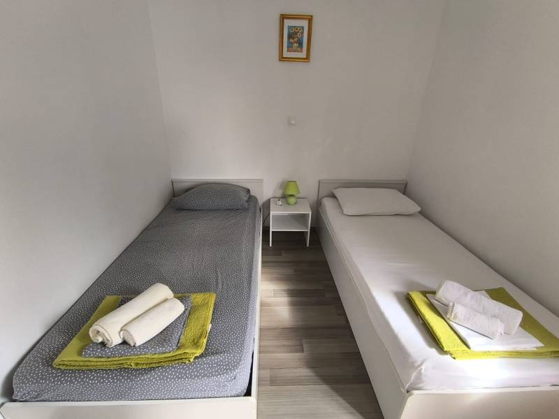 A bright bedroom in a 3-room apartment with two single beds and a wooden decor floor.