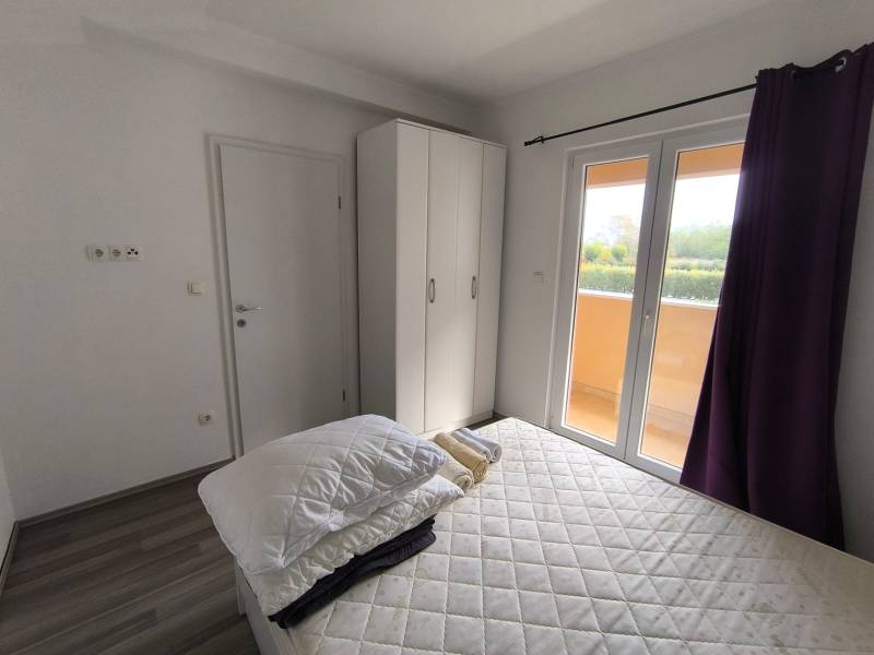Bedroom with a wardrobe, bed, and view from a 3-room apartment with a wooden decor floor.