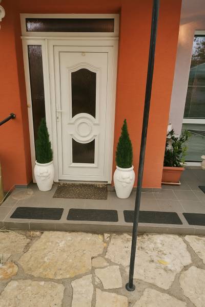 The entrance door of a family house in Zlaté Moravce, surrounded by flower pots and stone paving.