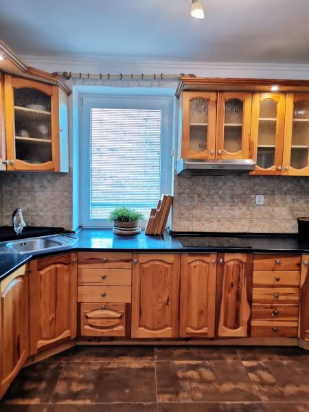 A kitchen in a family house with wooden cabinets and a tiled floor.