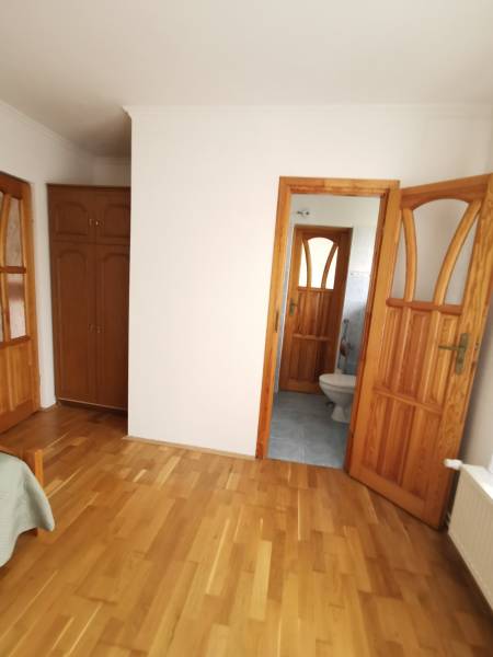 Interior of a family house with a wooden decor floor and a view into the bathroom.