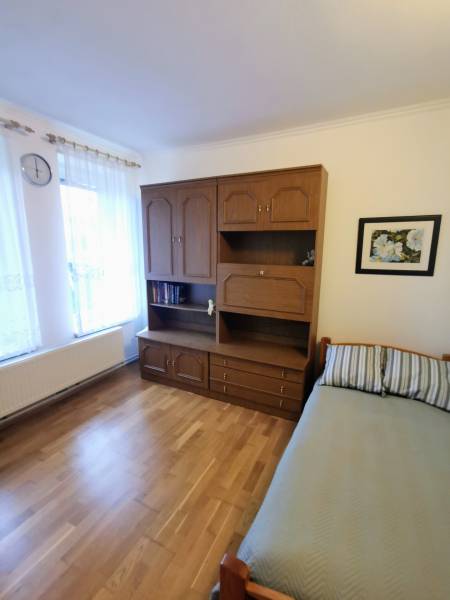 Interior of a family house with a bed, wardrobe, and floor with wooden decor.