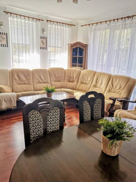 Living room with a cream sofa, wood-patterned floor, table with flowers.