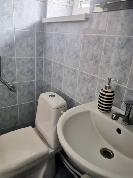 A bathroom in a family house with a sink, toilet, and gray tiles.