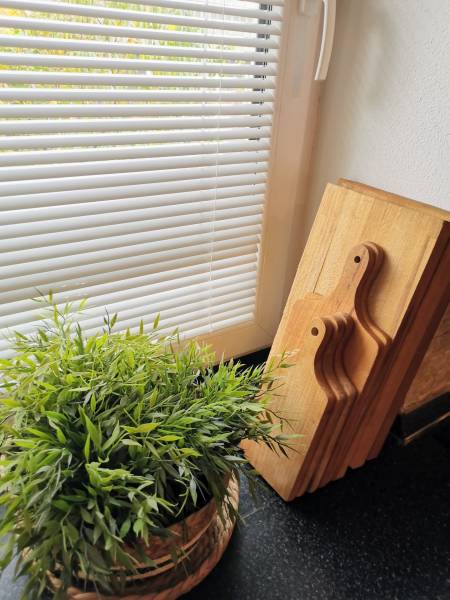 A room in a family house with a flower and wooden boards on a black kitchen counter.