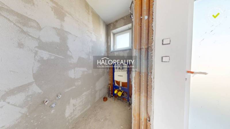 Bathroom space in a family house with rough walls and a window.