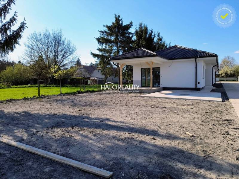 A family house with a garden on flat terrain, surrounded by greenery and trees.