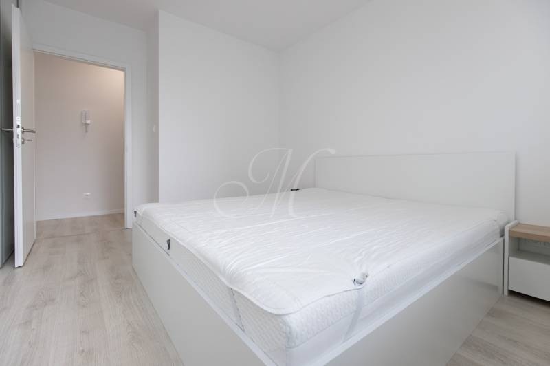 A bright bedroom with a bed and a wood-decor floor in a two-room apartment.