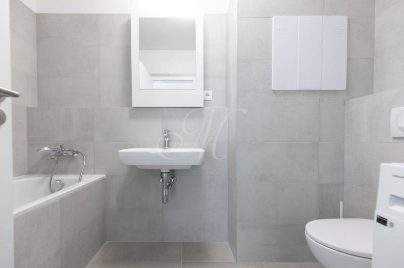 A bathroom with a shower, sink, and toilet in a 2-room apartment with tiled flooring.