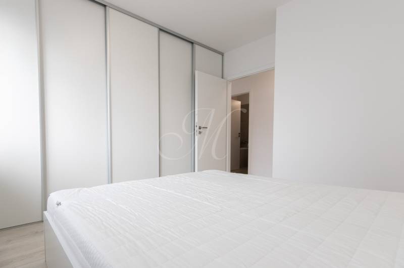 Bedroom in a 2-room apartment with a sliding wardrobe and a white bed.