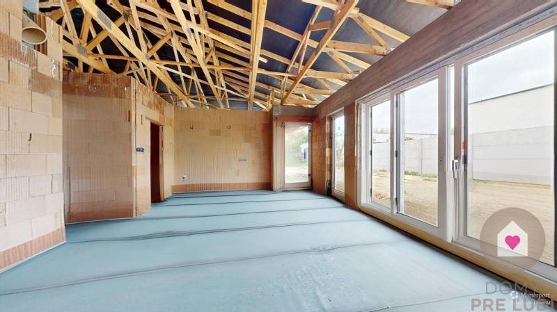 Construction of a family house with a roof structure and large windows without surface finishes.