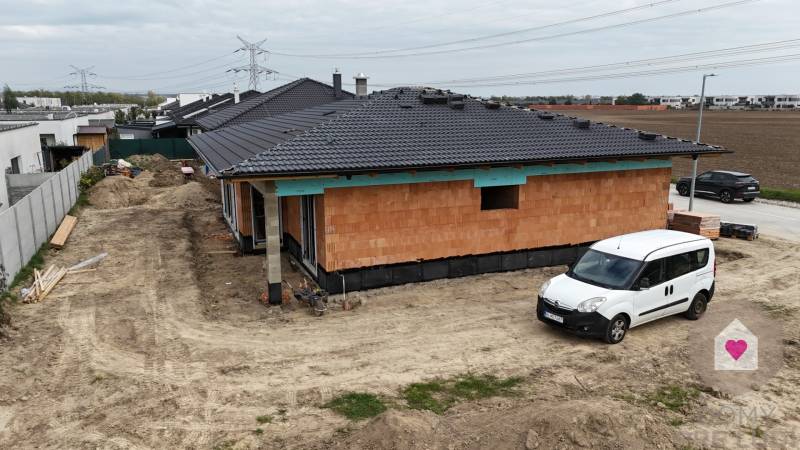 Construction of a family house in Bernolákovo with exposed bricks and parking on dirt.