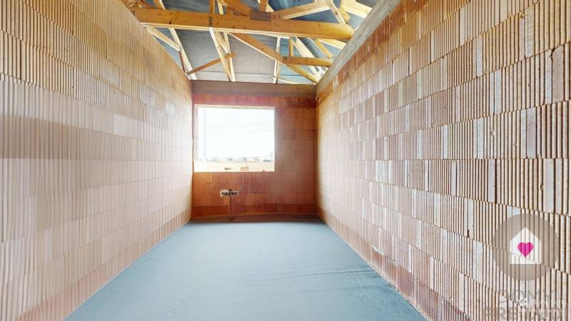 A room in a family house with brick walls and an unfinished floor.