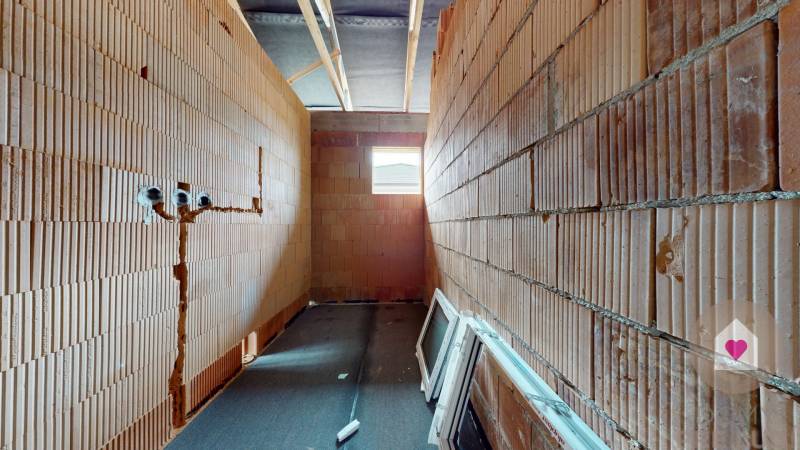 Construction of a family house with visible brick walls and ceiling beams.