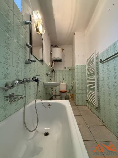 A bathroom in a family house, with a bathtub, sink, toilet, and light green tile decor.