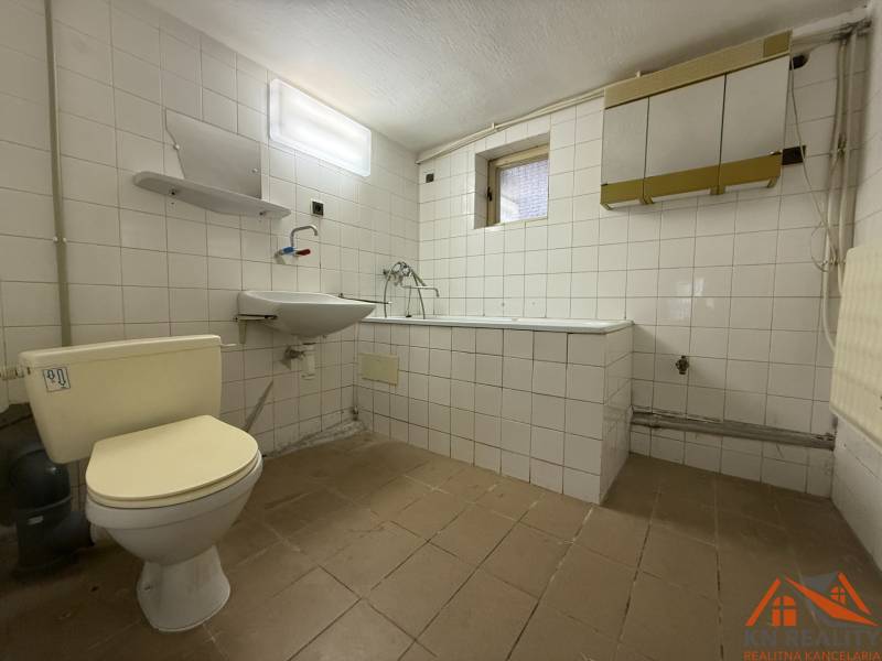 Bathroom with white tiles, a toilet, and a bathtub in a family house.